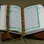 close up shot of a book beside prayer beads