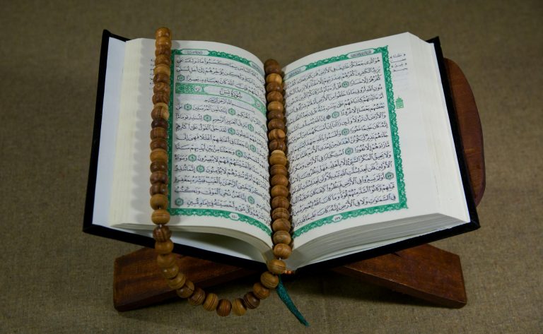 close up shot of a book beside prayer beads