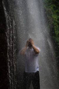 man enjoying refreshing waterfall shower